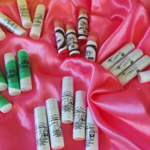 5 groups of assorted lip balms spread across a pink satin cloth