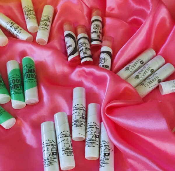 5 groups of assorted lip balms spread across a pink satin cloth
